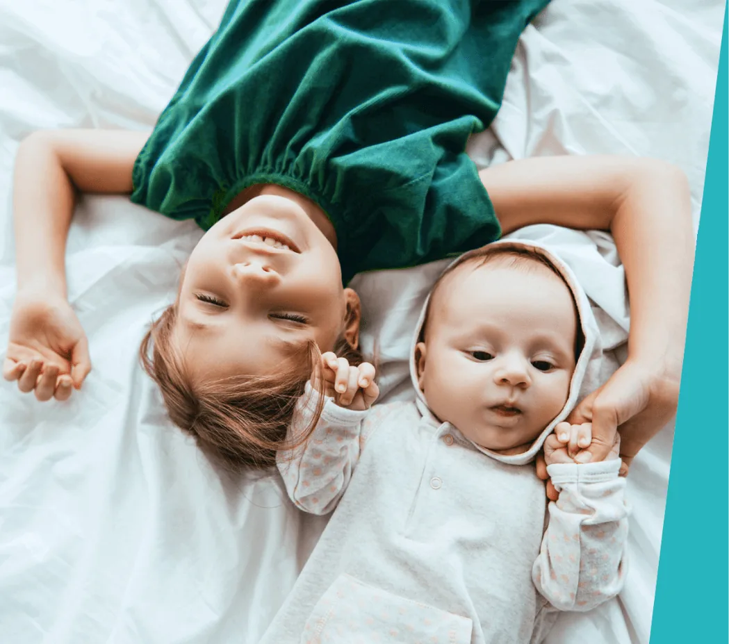 Little girl lying next to her baby brother