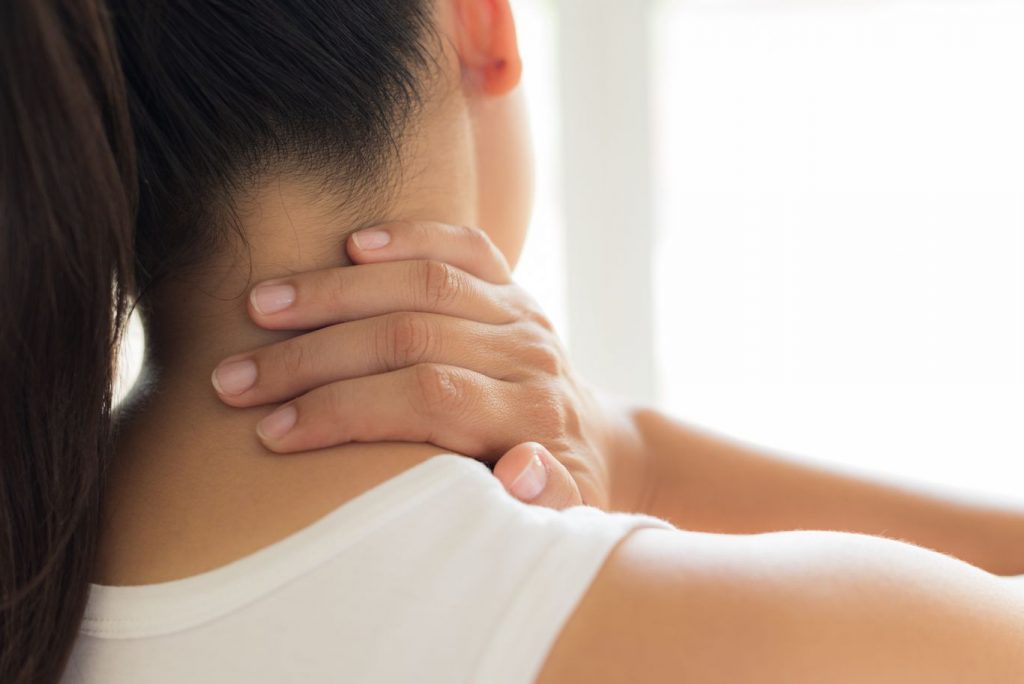 Woman with neck pain touching her neck