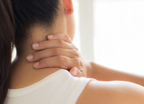 Woman with neck pain touching her neck